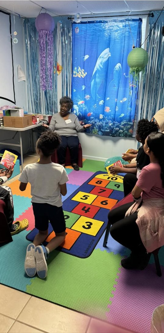 A volunteer reads aloud to children in the reading circle